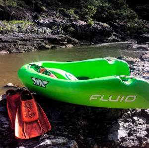 a green motorcycle parked on the side of a lake