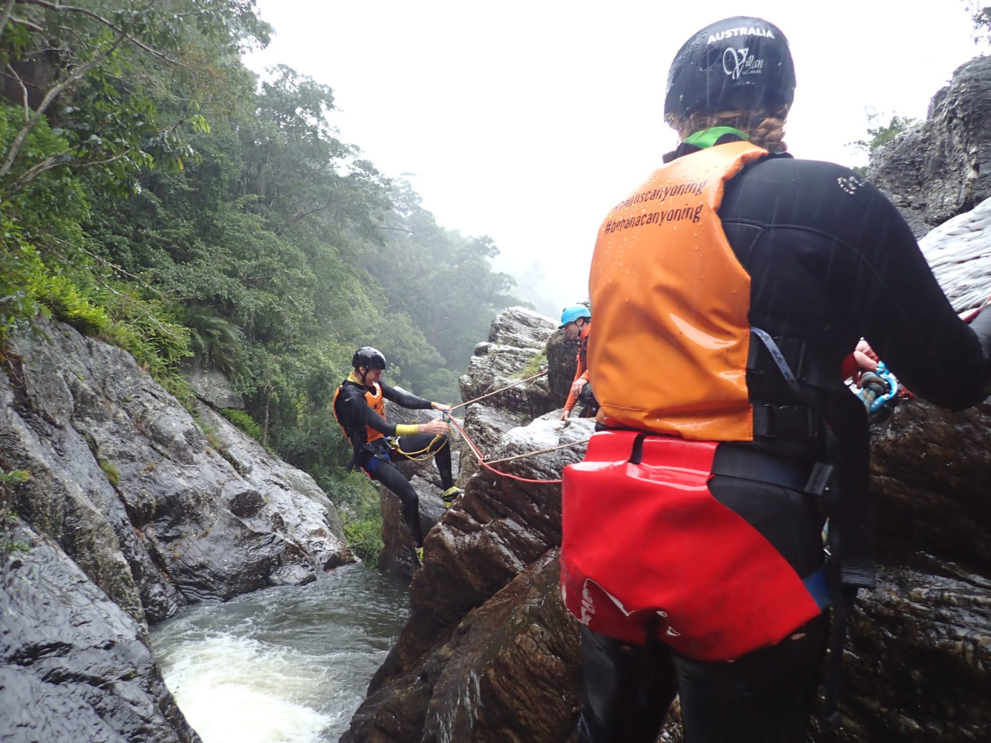 people experiencing the Spillway Full Day Canyoning Tour at a waterfall in Cairns