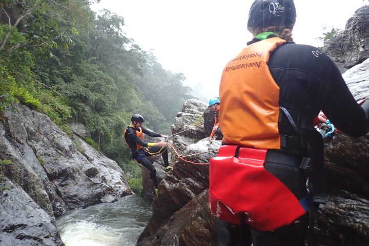 people experiencing the Spillway Full Day Canyoning Tour at a waterfall in Cairns