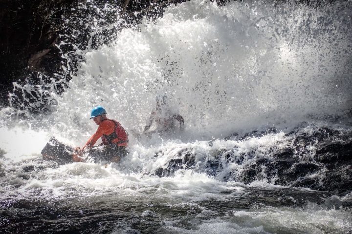 people experiencing the Spillway Full Day Canyoning Tour at a waterfall in Cairns